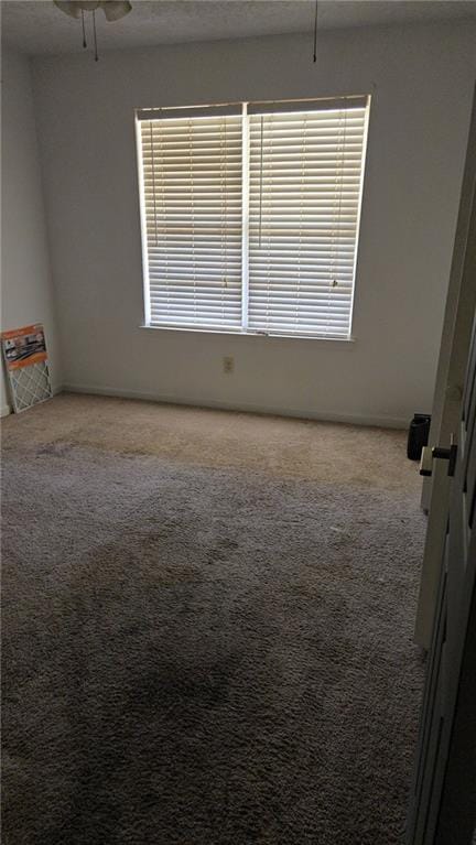 empty room featuring carpet floors, ceiling fan, and a wealth of natural light