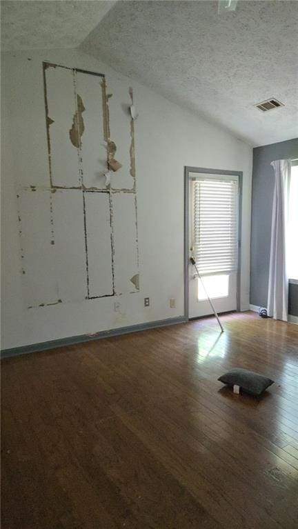 unfurnished room featuring visible vents, baseboards, lofted ceiling, and wood finished floors