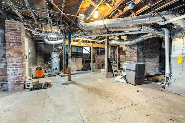 basement featuring brick wall, water heater, and stainless steel refrigerator