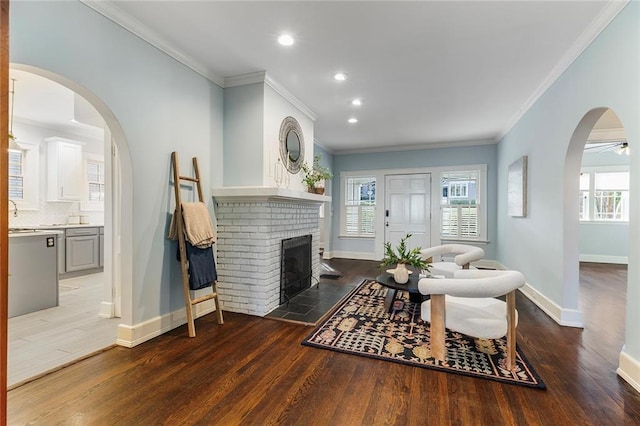 living room with ceiling fan, dark wood-type flooring, crown molding, and a fireplace