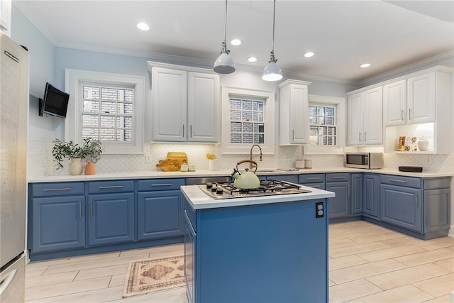 kitchen with stainless steel appliances, blue cabinets, white cabinets, hanging light fixtures, and a kitchen island