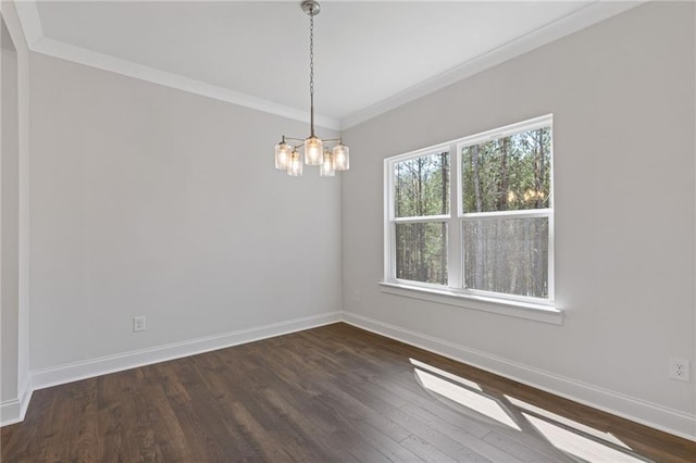 spare room featuring an inviting chandelier, ornamental molding, baseboards, and dark wood-style floors