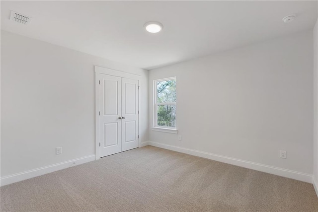 unfurnished room featuring baseboards, light carpet, and visible vents