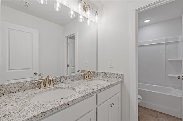 bathroom featuring double vanity, a sink, tile patterned flooring, and toilet