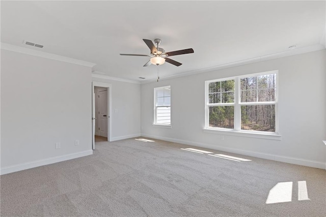 empty room featuring baseboards, ornamental molding, a ceiling fan, and light colored carpet