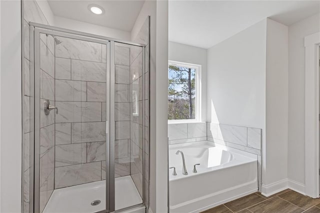 bathroom featuring baseboards, a shower stall, a bath, and wood finished floors