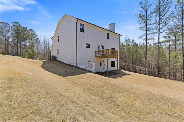 back of property with a yard, a chimney, central air condition unit, and a wooden deck