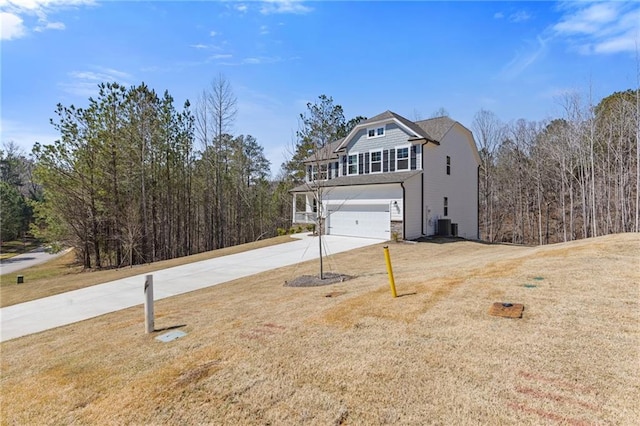 view of side of home featuring concrete driveway, a yard, central AC unit, and a garage