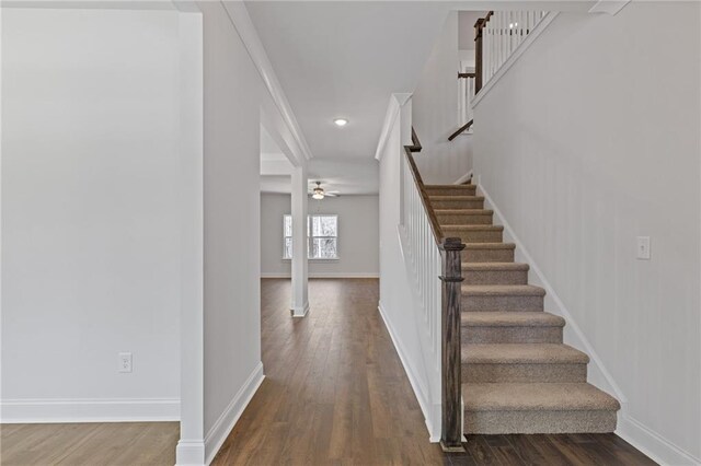 stairway with baseboards, ceiling fan, and wood finished floors