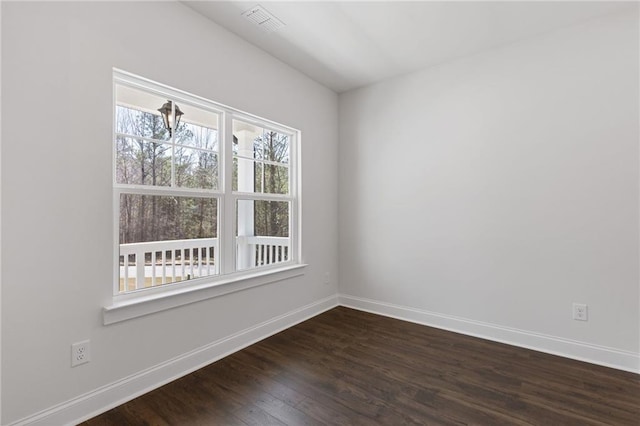 spare room featuring baseboards, dark wood-style floors, and visible vents