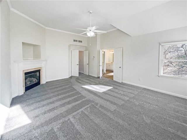 unfurnished living room with a tile fireplace, visible vents, baseboards, dark carpet, and crown molding