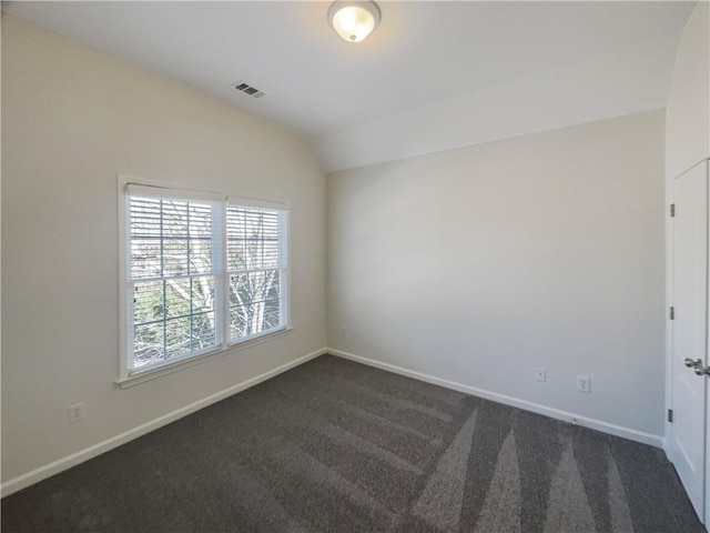 unfurnished room featuring dark colored carpet, visible vents, vaulted ceiling, and baseboards