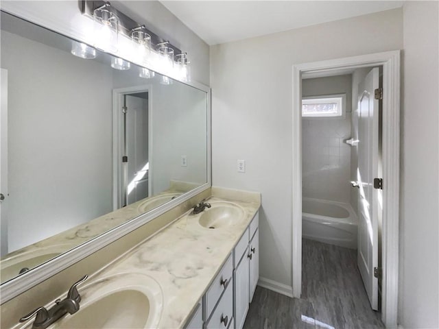 full bathroom featuring bathtub / shower combination, wood finished floors, a sink, and double vanity