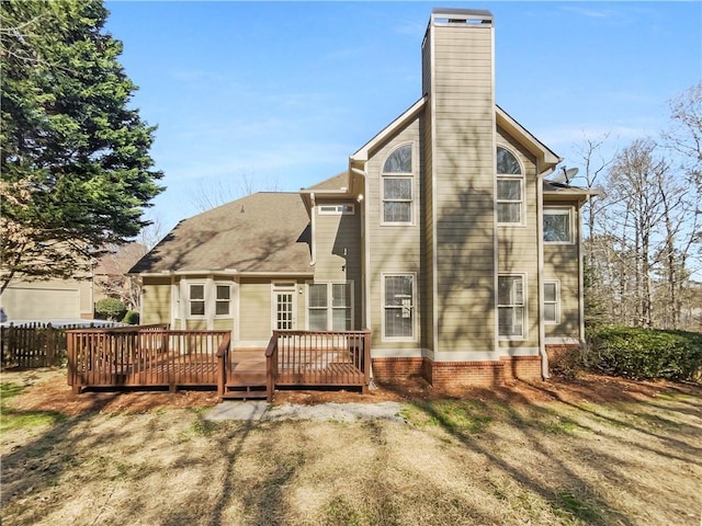 back of property with a chimney, fence, a lawn, and a wooden deck