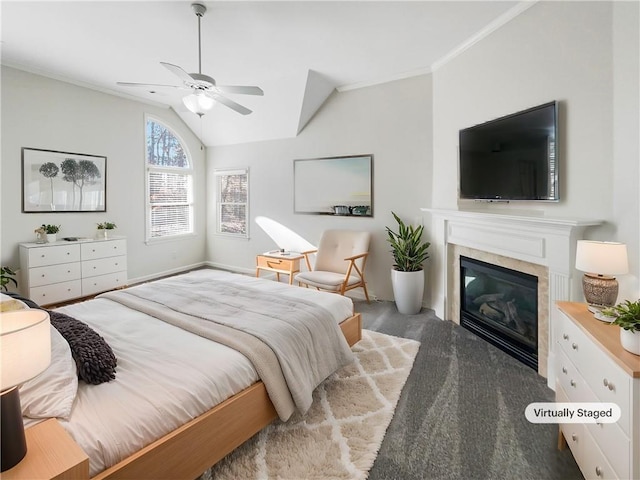 bedroom with a ceiling fan, a glass covered fireplace, lofted ceiling, ornamental molding, and dark colored carpet