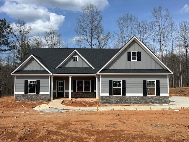 craftsman-style house featuring a porch, stone siding, board and batten siding, and a shingled roof