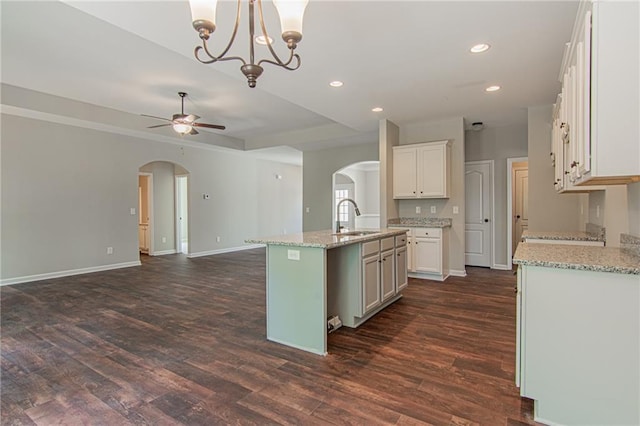 kitchen featuring open floor plan, ceiling fan with notable chandelier, arched walkways, and dark wood-style flooring