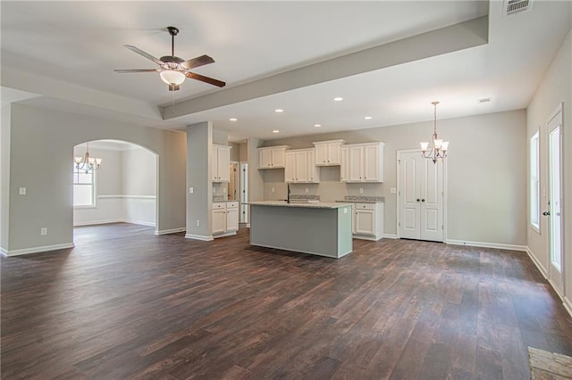 kitchen with visible vents, a center island with sink, ceiling fan with notable chandelier, open floor plan, and dark wood-style flooring