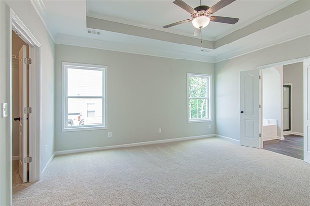 unfurnished bedroom with visible vents, baseboards, a tray ceiling, ornamental molding, and carpet floors