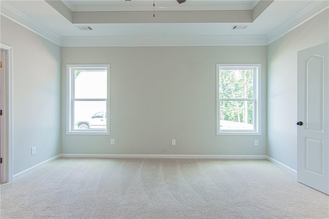 empty room featuring visible vents, carpet, a tray ceiling, ornamental molding, and a ceiling fan