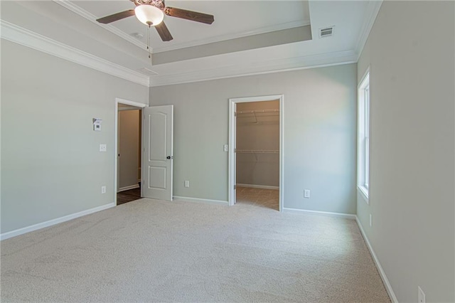 unfurnished bedroom with visible vents, carpet, baseboards, ornamental molding, and a raised ceiling