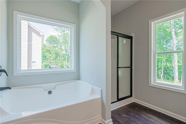 bathroom featuring a garden tub, wood finished floors, a stall shower, and a wealth of natural light