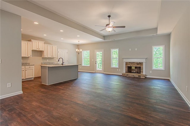 kitchen with a raised ceiling, dark wood-style flooring, and ceiling fan with notable chandelier