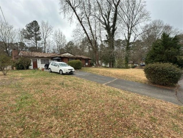 exterior space with a front yard, driveway, and a chimney