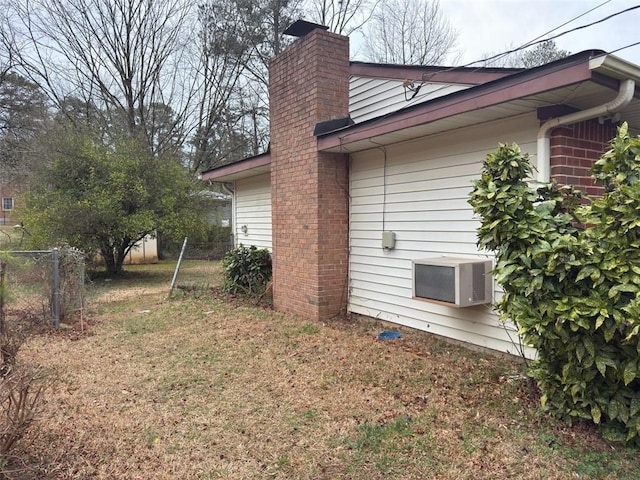 view of home's exterior featuring brick siding, a chimney, and fence