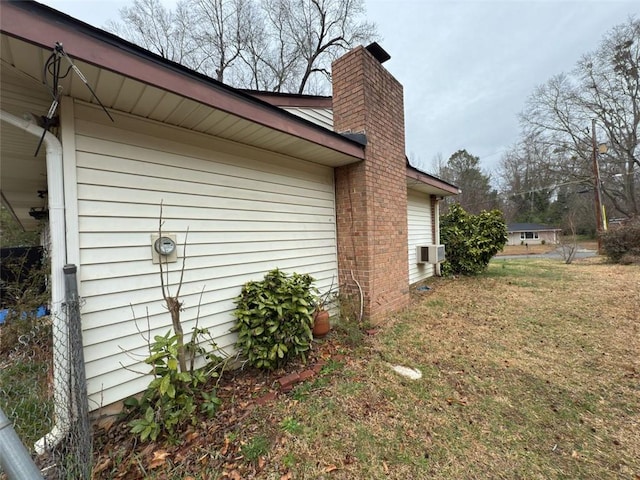 view of side of property with cooling unit, a yard, and a chimney