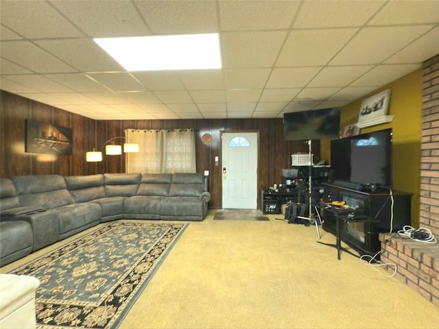 carpeted living area featuring a drop ceiling and wooden walls