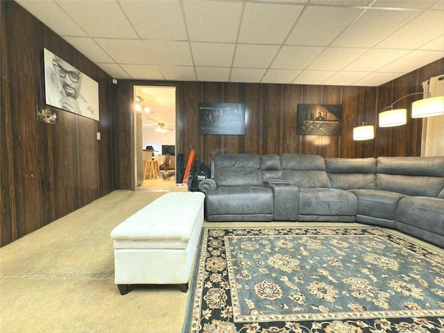 living area featuring a paneled ceiling, wooden walls, and carpet flooring