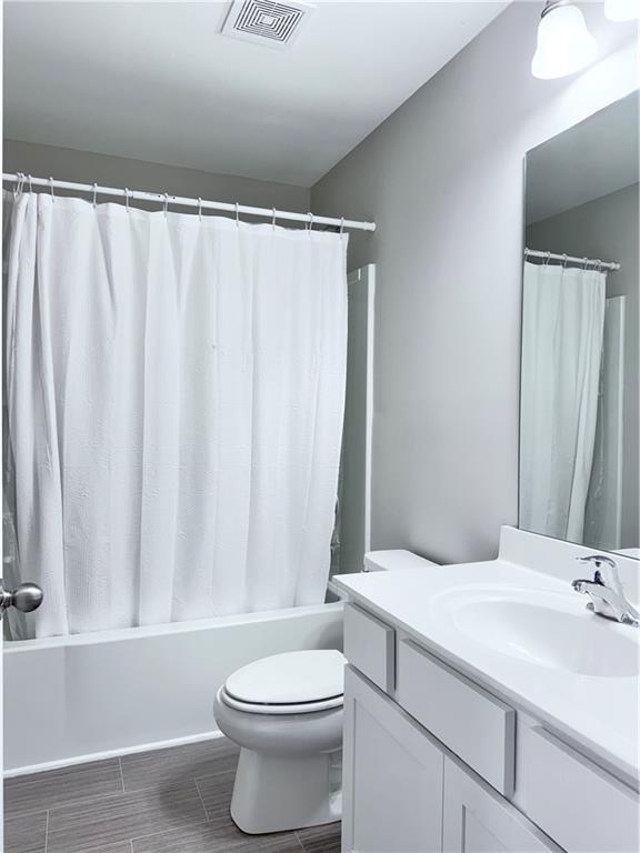 full bathroom featuring shower / bathtub combination with curtain, vanity, and toilet