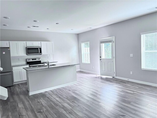 kitchen with wood-type flooring, white cabinets, an island with sink, and stainless steel appliances