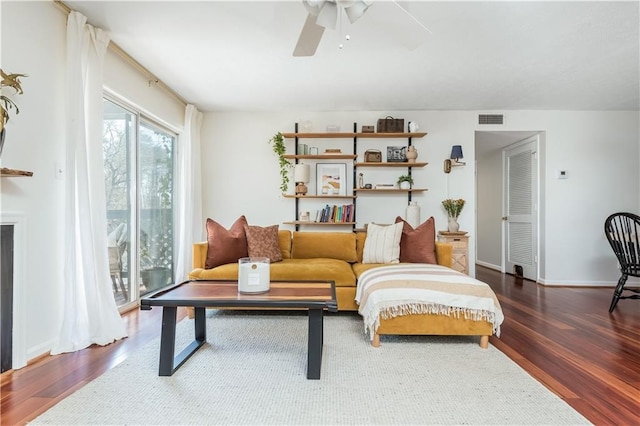 sitting room with a ceiling fan, wood finished floors, visible vents, and baseboards