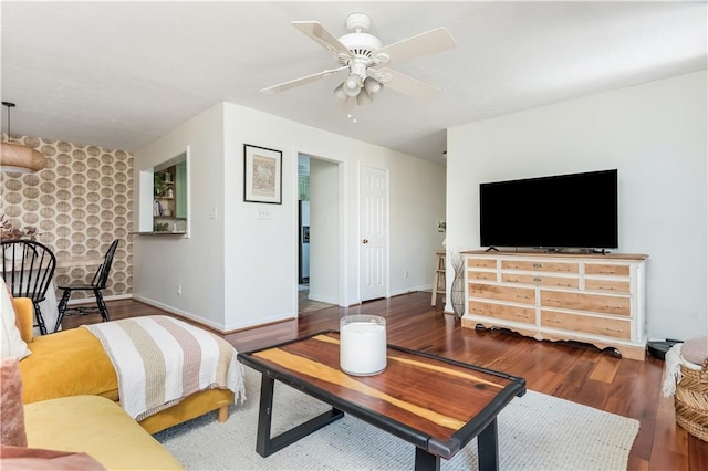 living room with a ceiling fan, baseboards, and wood finished floors