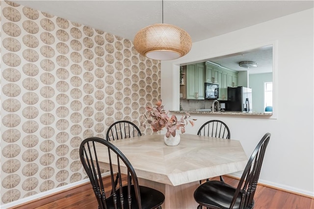 dining space with baseboards and wood finished floors