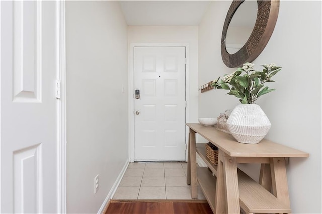 doorway featuring light tile patterned flooring and baseboards