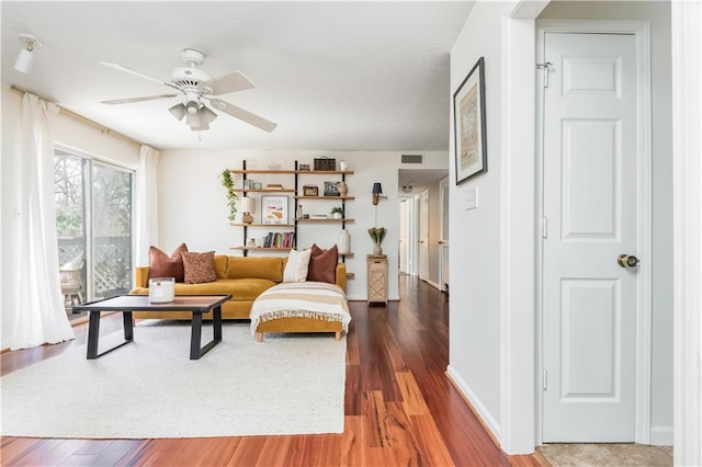 living room with baseboards, wood finished floors, visible vents, and a ceiling fan