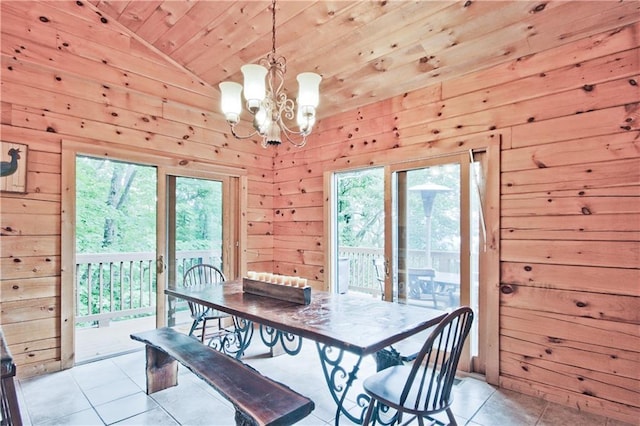 dining area with wood walls, light tile patterned floors, vaulted ceiling, and an inviting chandelier