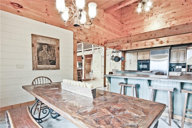 dining area featuring beam ceiling, wood walls, and a chandelier