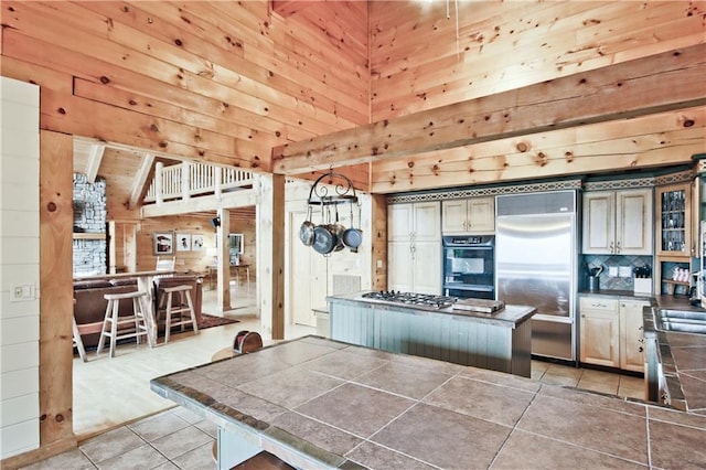 kitchen with wooden walls, a center island, light tile patterned floors, and stainless steel appliances