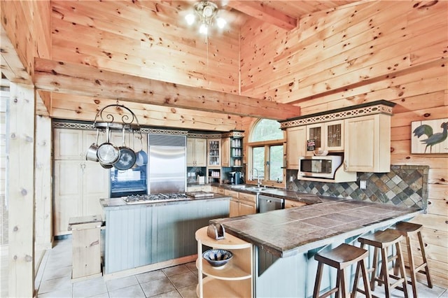 kitchen with wooden walls, light tile patterned floors, stainless steel appliances, and a kitchen island