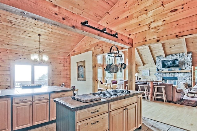 kitchen featuring vaulted ceiling with beams, hanging light fixtures, stainless steel gas stovetop, a center island, and wood ceiling