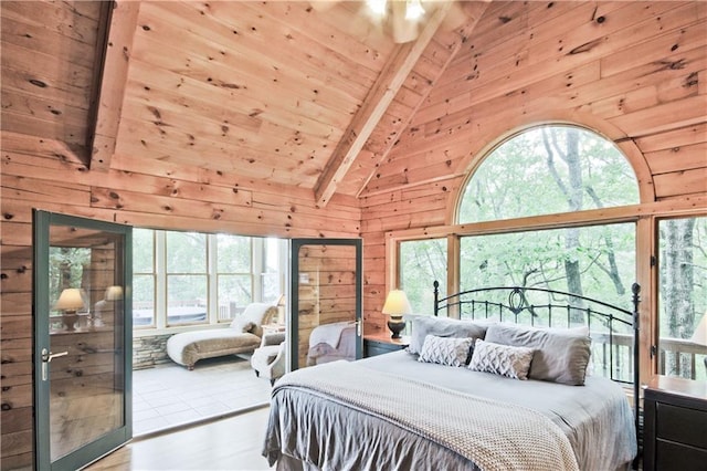 bedroom featuring beamed ceiling, light wood-type flooring, multiple windows, and wood walls