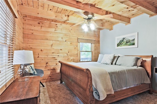 bedroom with ceiling fan, dark colored carpet, beamed ceiling, wooden walls, and wood ceiling