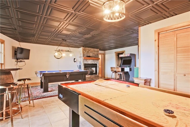 game room featuring a stone fireplace, light tile patterned floors, and pool table