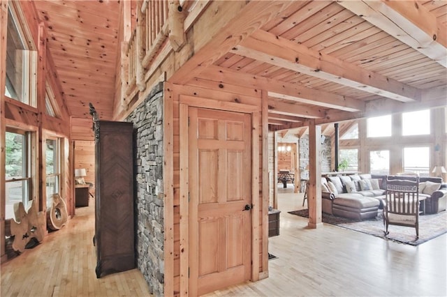 interior space featuring a high ceiling, wooden ceiling, a healthy amount of sunlight, and light hardwood / wood-style floors