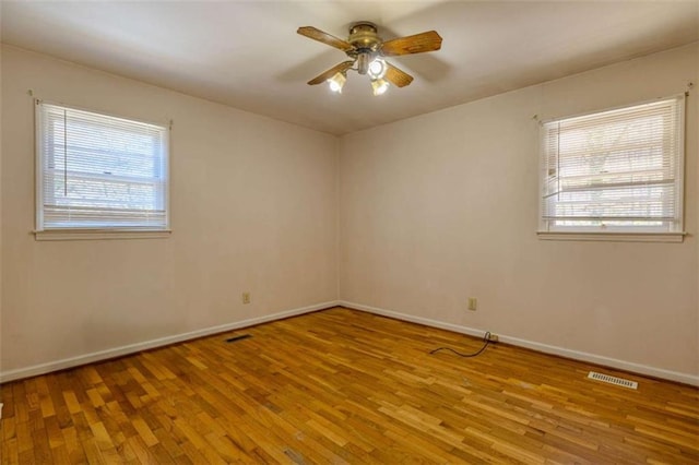 empty room featuring plenty of natural light, wood finished floors, and a ceiling fan