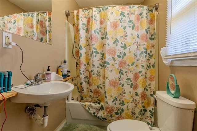 bathroom featuring toilet, a sink, and shower / bathtub combination with curtain